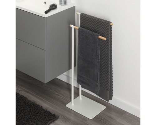 Porte-serviettes autoportant en métal et bois avec deux serviettes grises dans la salle de bains.