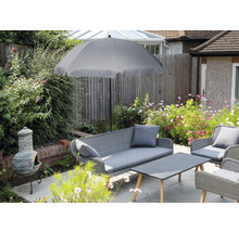 Gartenszene mit grauem Sonnenschirm, Rattansitzgruppe und Lehmofen auf einer Terrasse