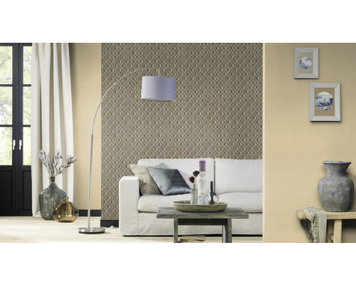 Salon avec papier peint à motifs, canapé, lampadaire et éléments décoratifs pour une ambiance chaleureuse.