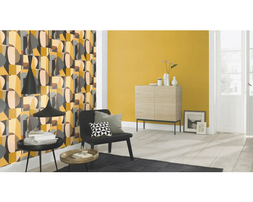 Salon avec papier peint à motifs, commode et fauteuil.