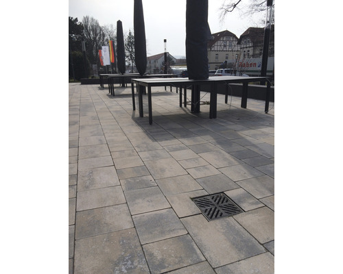 Espace extérieur avec pavés, bouche d''égout, tables et housses de parasols