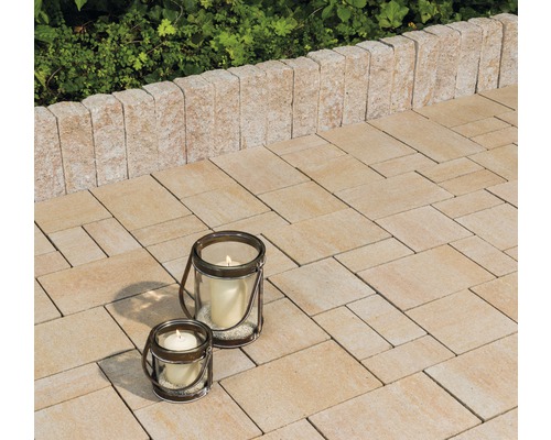 Gepflasterte Terrasse mit Kerzenlaternen und Begrenzungsmauer