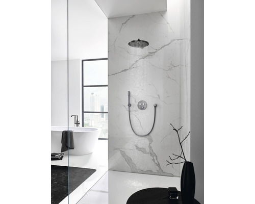 Salle de bains lumineuse avec douche de tête, douchette à main et robinetterie sur un mur en marbre.