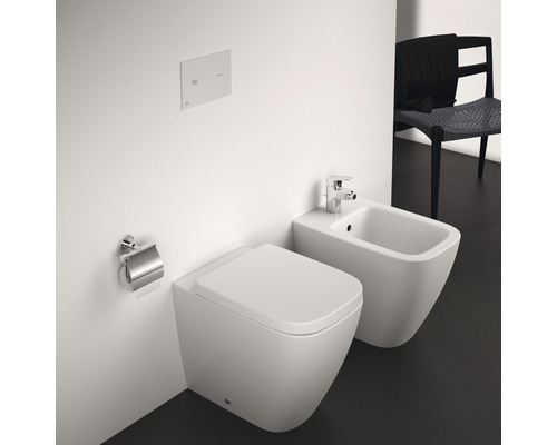 WC suspendu et bidet dans une salle de bains avec porte-papier toilette et plaque de commande