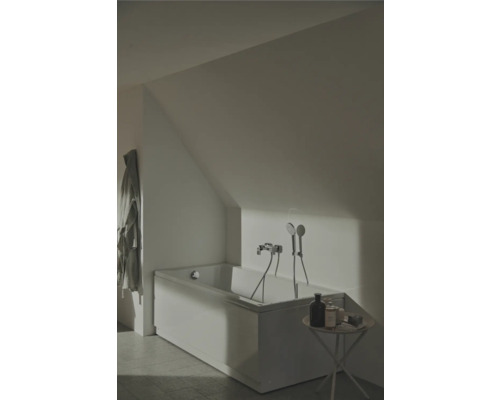 Salle de bains avec baignoire sous pente de toit, robinetterie et petite table