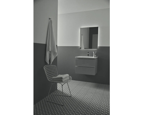 Salle de bains moderne avec meuble-lavabo, miroir éclairé, serviette et carrelage décoratif