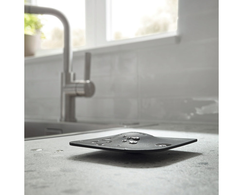 Schwarze Spülbeckenablage mit Wassertropfen in einer Küchenspüle.