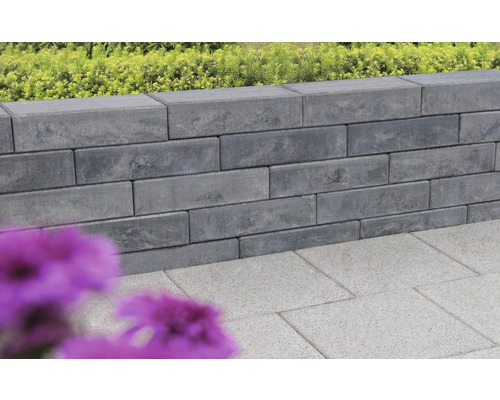 Graue Mauer aus Betonsteinen und Bodenplatten im Garten