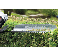 Eine Heckenschere von Einhell schneidet eine grüne Hecke.