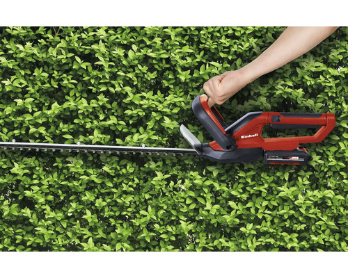 Eine Person benutzt eine Akku-Heckenschere von Einhell, um eine Hecke zu schneiden.