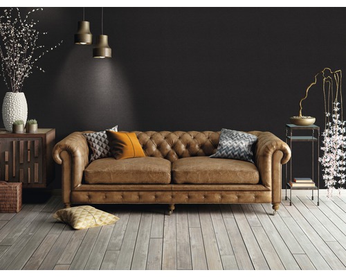 Salon avec un canapé en cuir marron de style Chesterfield, parquet en bois et éléments décoratifs