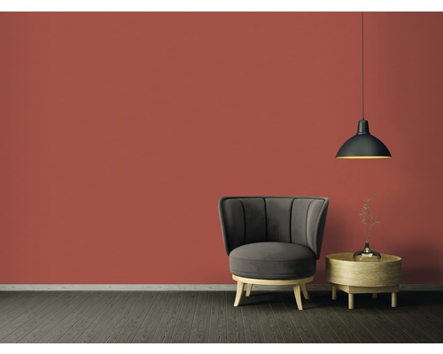 Salon avec fauteuil, table d''appoint et suspension devant un mur coloré