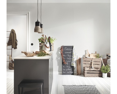 Heller Küchenbereich mit Kücheninsel, Hocker, Beleuchtung, Kreidetafel und dekorativen Küchenutensilien.