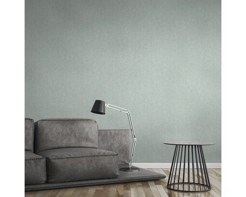 Salon avec canapé gris, lampe et petite table devant un papier peint à motifs