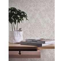 Tapete mit floralem Muster im Interieur mit Tisch, Pflanze und Büchern