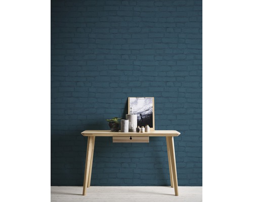 Szene mit einer Holzkonsole vor einer Wand in Ziegeloptik, dekoriert mit Pflanze, Kerzenständern und einem Bild