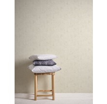 Dekorative Kissen gestapelt auf einem Hocker vor einer Wand