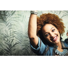 Frau mit gemusterter Tapete mit tropischen Blättern im Hintergrund