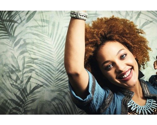 Frau mit gemusterter Tapete mit tropischen Blättern im Hintergrund