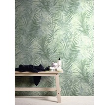 Raum mit einer Wandtapete mit Palmenmuster und einer Holzbank mit Textilien und Badutensilien.