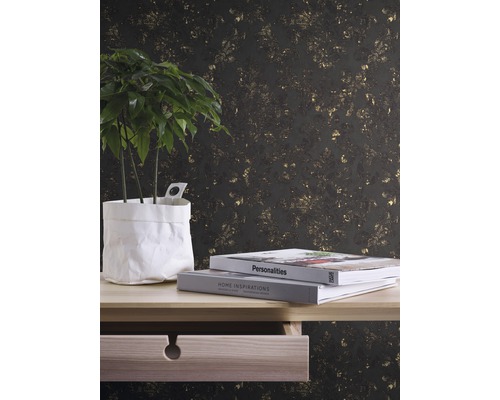 Dekorative Tapete mit Pflanzenmuster hinter einem Tisch mit Topfpflanze und Büchern