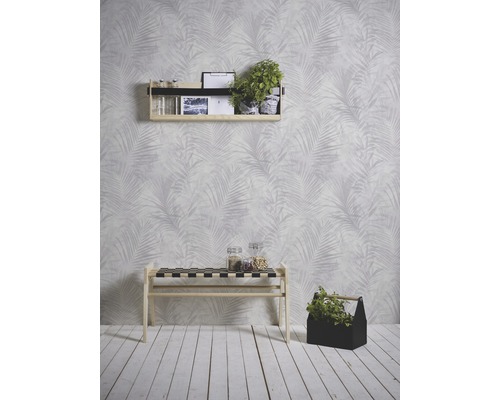 Wohnraum mit Regal, Bank und Dekoration vor einer Wand mit Palmenmuster.