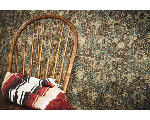 Chaise en bois avec couverture devant un papier peint à motifs