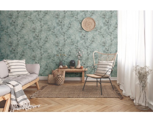 Salon avec papier peint à motifs, canapé, chaise et décorations pour une ambiance chaleureuse.