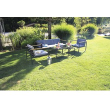 Gartenszene mit Loungemöbelset mit Sofa, Sesseln und Tischen auf einer Rasenfläche