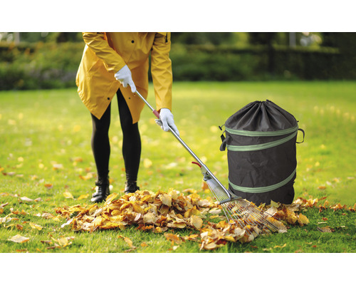 Femme avec râteau et sac de jardinage lors de travaux de jardinage