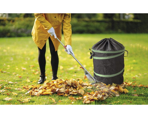 Femme ramassant des feuilles mortes avec un râteau et un sac de jardin