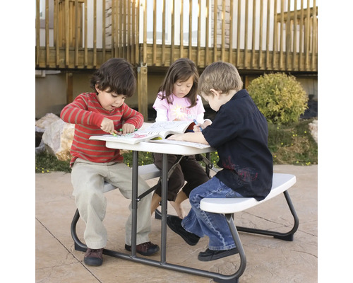 Des enfants sont assis à une table de pique-nique et colorient dans des livres.