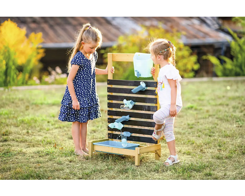 Deux enfants jouent avec une piste d''eau dans le jardin.