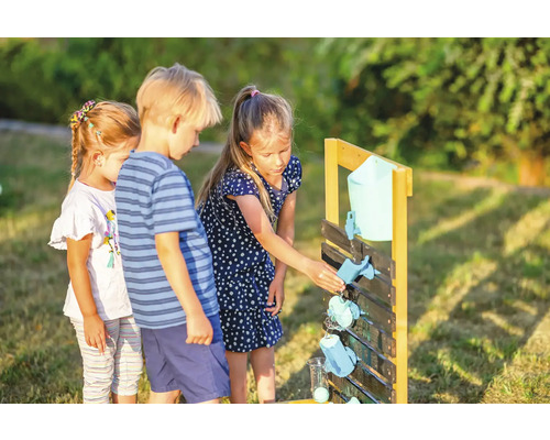 Des enfants jouent avec un parcours d''eau en bois dans le jardin.