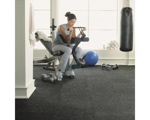 Fitnessraum mit Frau beim Training an Hantelbank auf Gummiboden