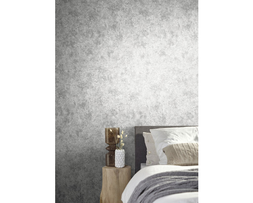 Chambre avec papier peint gris imitation béton, lit et table d''appoint en bois.