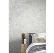 Chambre claire avec lit, table de chevet et objets décoratifs devant un mur gris