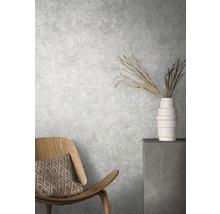 Intérieur décoratif avec chaise, coussin, vase et plantes ornementales devant un mur texturé