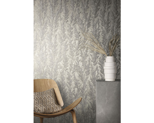 Vue d''une pièce avec du papier peint structuré à motif végétal, un fauteuil en bois et un vase blanc.