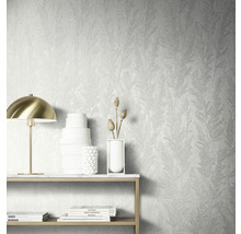 Décoration murale avec papier peint structuré à motif végétal, table avec décoration et lampe