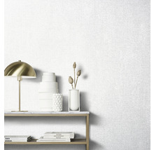 Papier peint clair avec une structure en tissu dans le salon avec une table et des objets décoratifs.