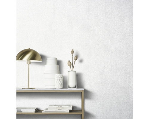 Papier peint clair avec une structure en tissu dans le salon avec une table et des objets décoratifs.