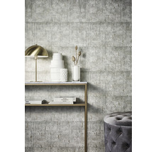 Espace de vie avec papier peint béton gris, console, lampe et pouf