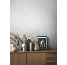 Pièce lumineuse avec papier peint gris clair et commode en bois avec décorations