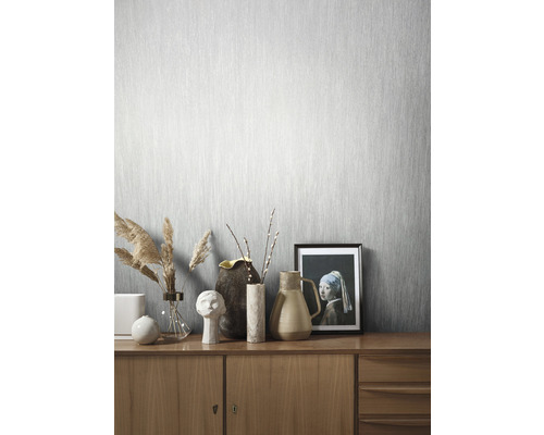 Pièce lumineuse avec papier peint gris clair et commode en bois avec décorations