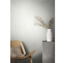 Scène avec un papier peint intissé clair, une chaise en bois avec coussin et un vase avec décoration sur un socle