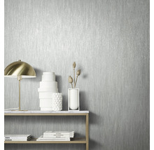 Gros plan d''un papier peint argenté avec un motif à rayures verticales dans une pièce lumineuse.