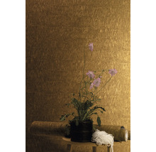 Nahaufnahme einer Wand mit einer Tapete mit Struktur, die auf einem kleinen Tisch mit einer Pflanze in einem Topf und einer Rolle Tapete dekoriert ist.