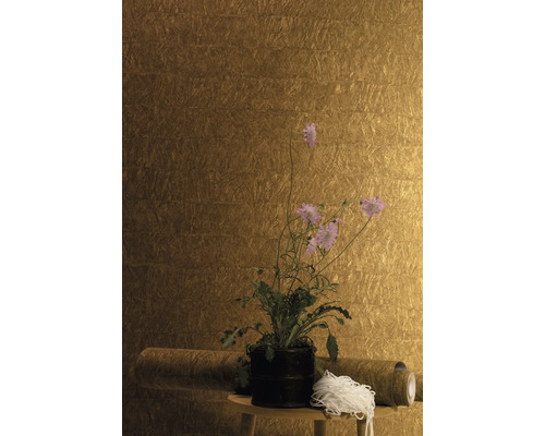 Nahaufnahme einer Wand mit einer Tapete mit Struktur, die auf einem kleinen Tisch mit einer Pflanze in einem Topf und einer Rolle Tapete dekoriert ist.