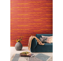 Salon avec papier peint vinyle orange, canapé, coussins et vase de fleurs